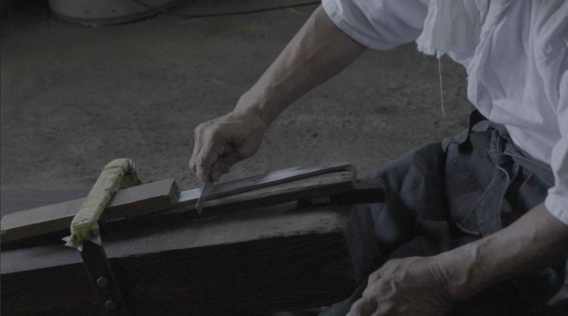 A craftsman polishing a Japanese sword blade by hand