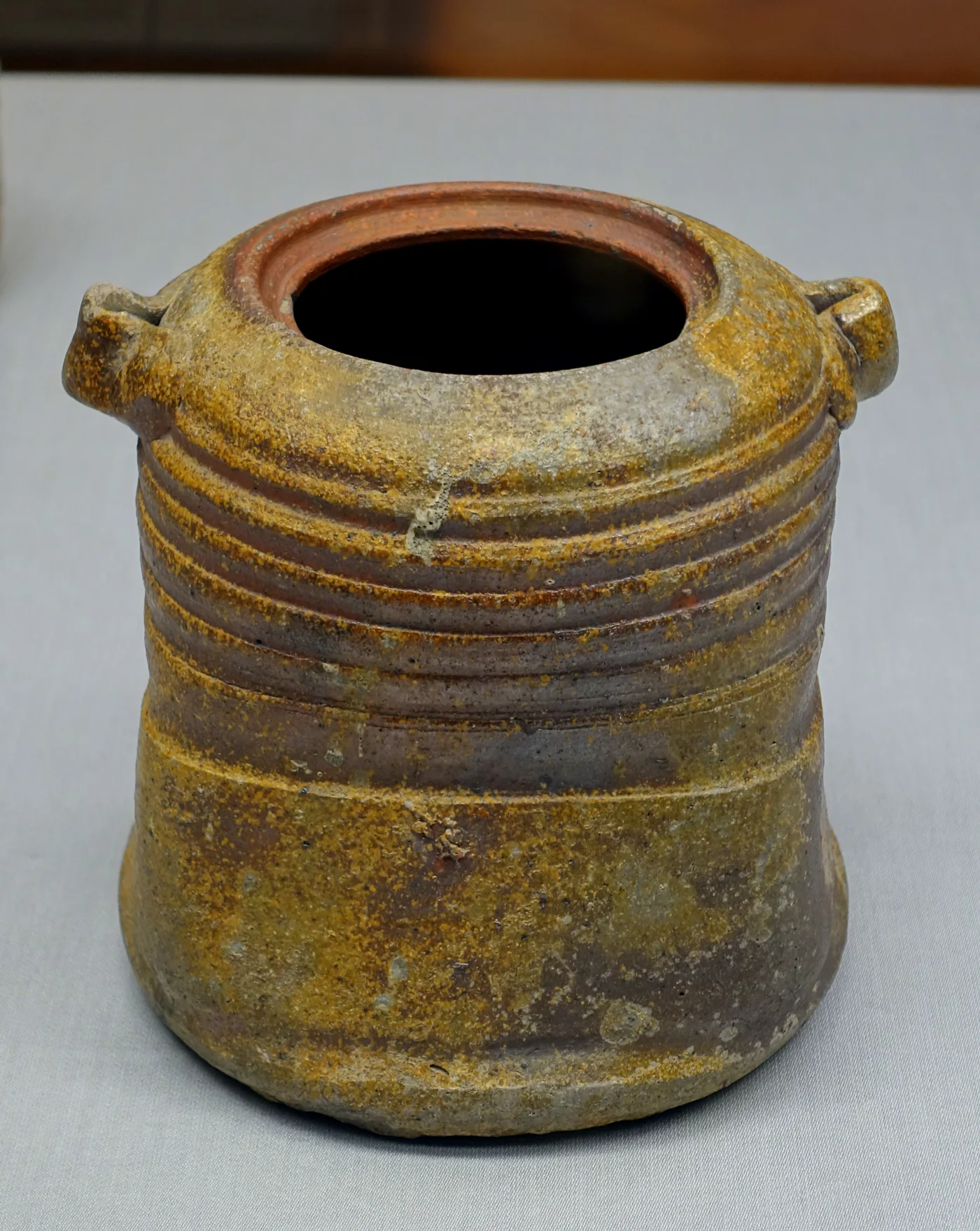 A brown, unglazed Bizen water jar with horizontal ridges and two lugs