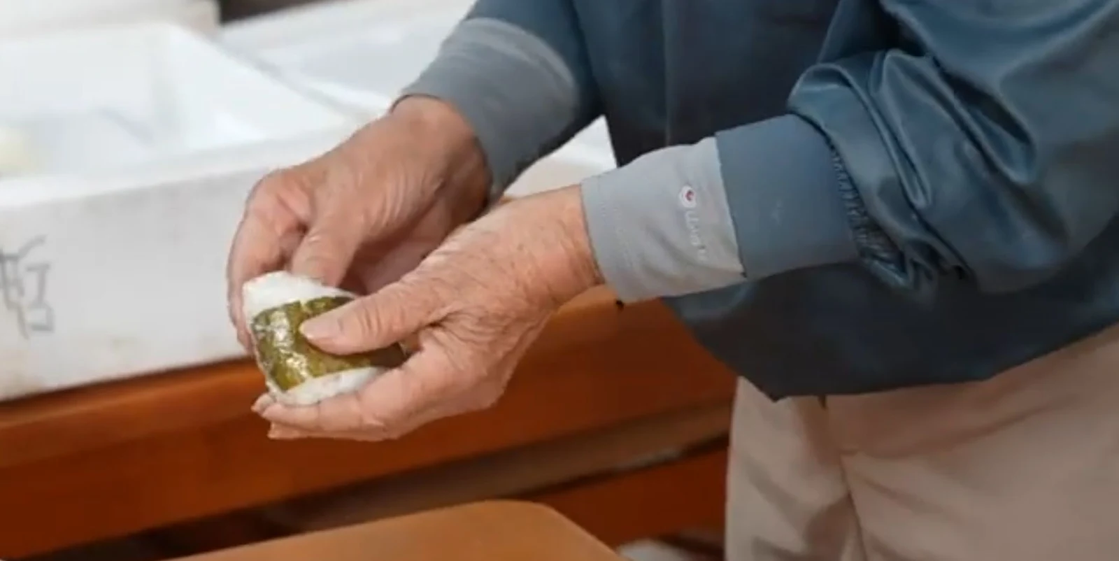 Hands wrapping a rice ball for high school students participating in a local river cleanup